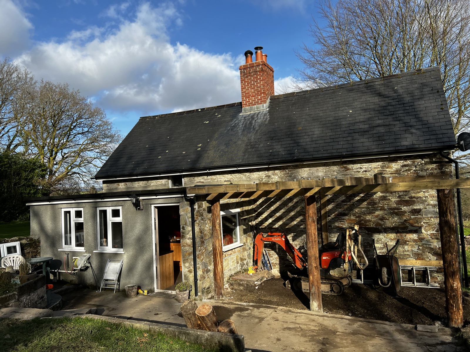 Timber pergola alongside a stone building